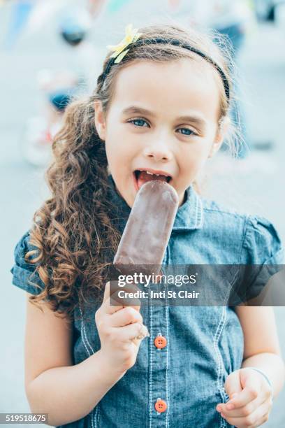 mixed race girl eating fudgesicle on city street - white fudge stock pictures, royalty-free photos & images