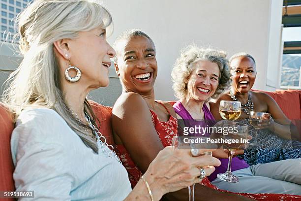 women drinking wine together on urban rooftop - four people foto e immagini stock