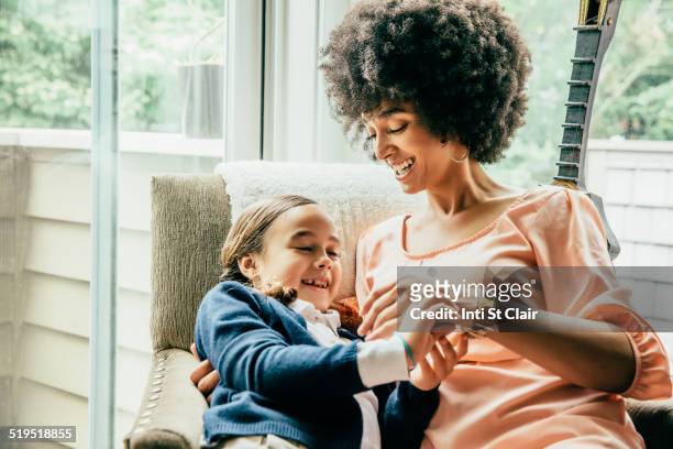 mixed race mother holding daughter in armchair - fashionable kids stock pictures, royalty-free photos & images