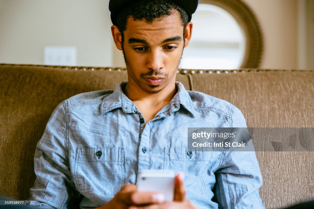 Mixed race boy using cell phone on sofa