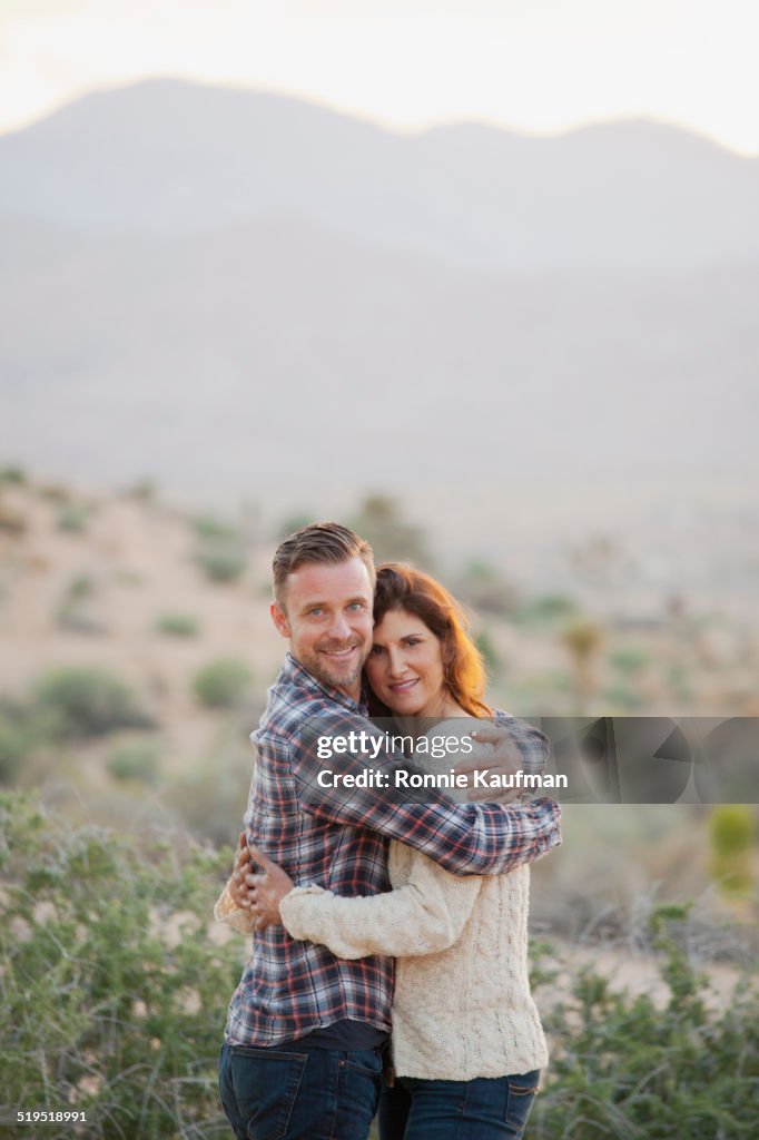 Caucasian couple hugging in desert
