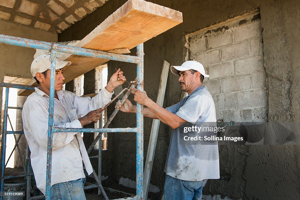 Hispanic construction workers with scaffolding at construction site