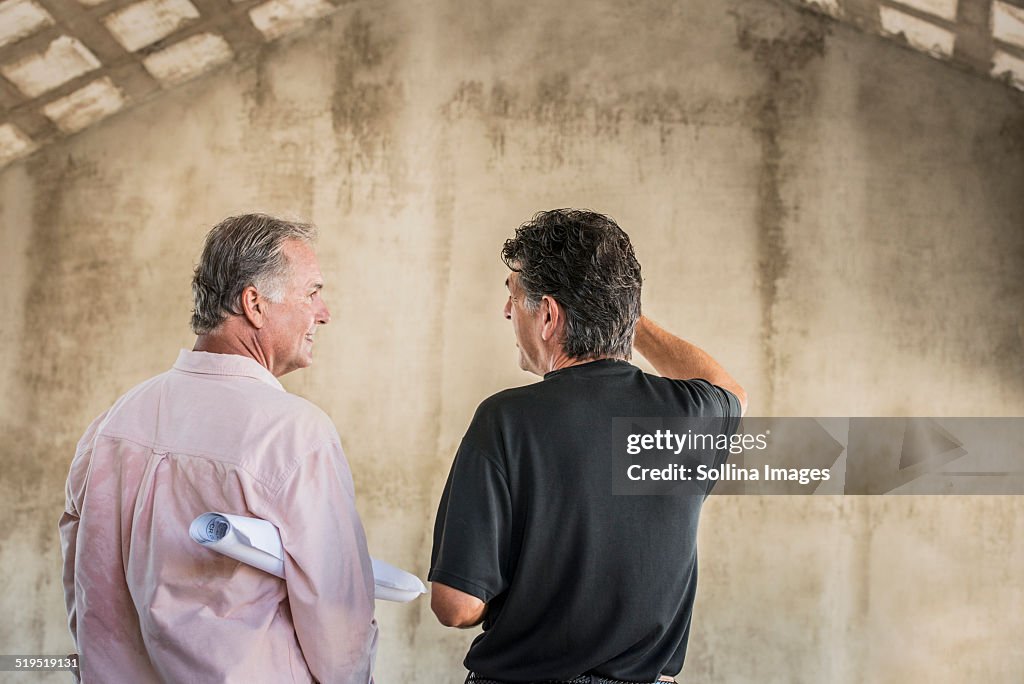 Caucasian architects talking near wall