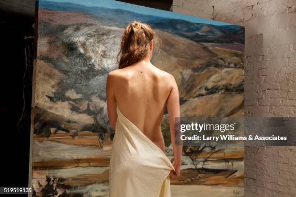 nude woman admiring painting in art gallery - female models photo gallery stockfoto's en -beelden