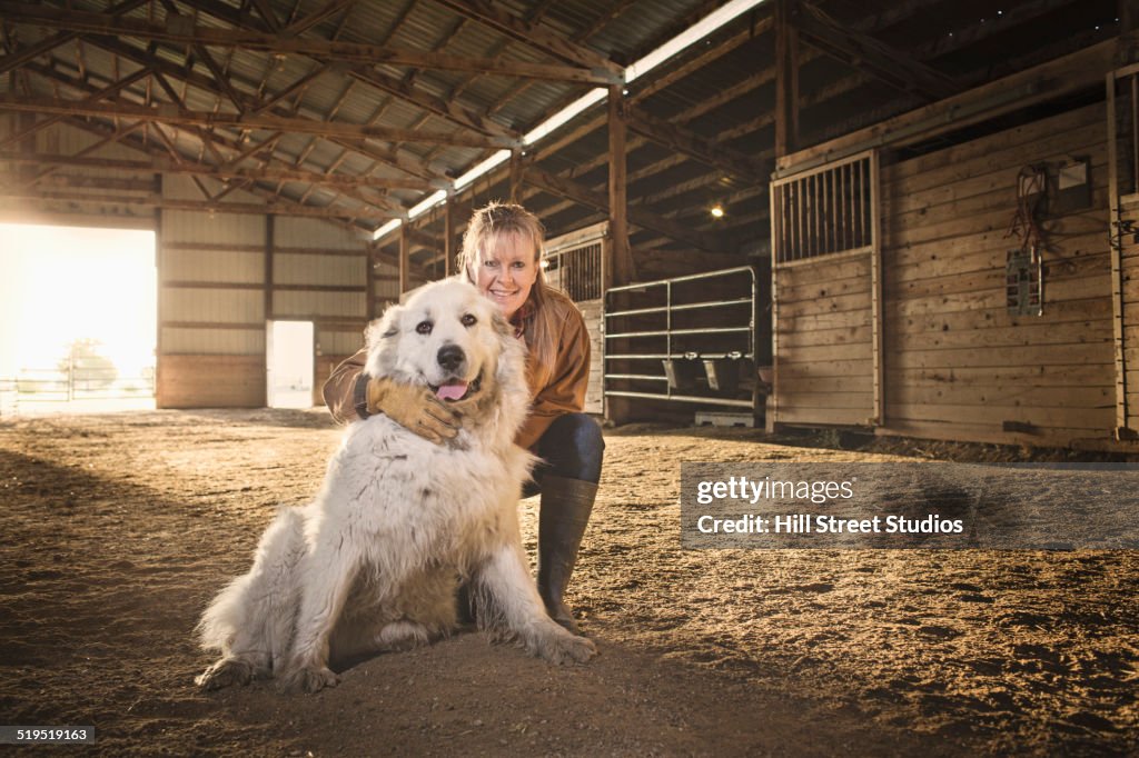 Caucasian farmer smiling with dog in barn