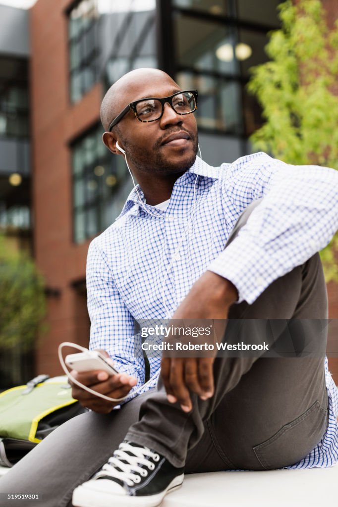 Black man listening to mp3 player in city