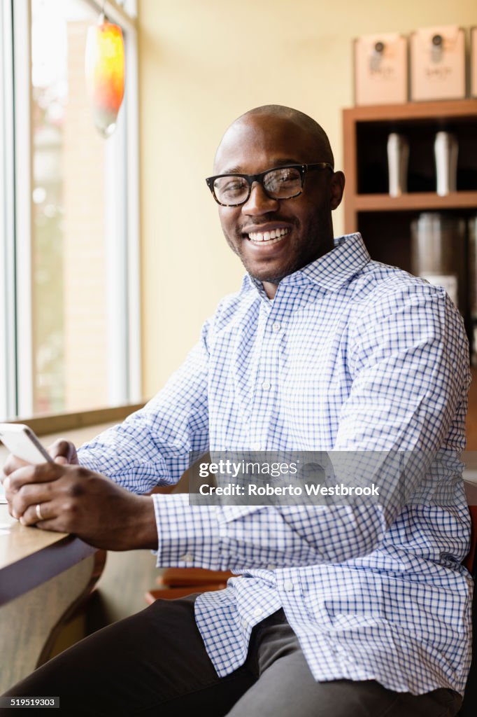Black man using cell phone in coffee shop