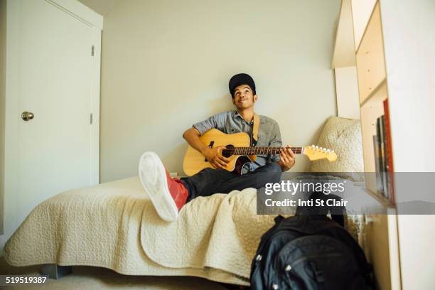 mixed race boy playing guitar in bedroom - boy bedroom stock pictures, royalty-free photos & images