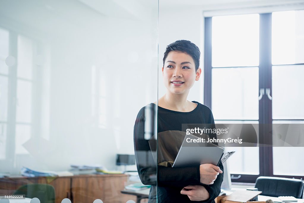 Businesswoman in modern office looking away through partition