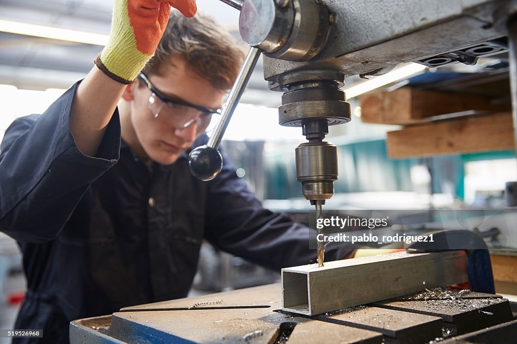 Young apprentice using pillar drill in steel fabrication factory