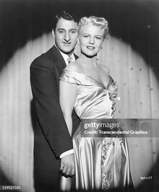 Promotional portrait of American singers Danny Thomas and Peggy Lee as they pose in front of a stage curtain, circa 1950.