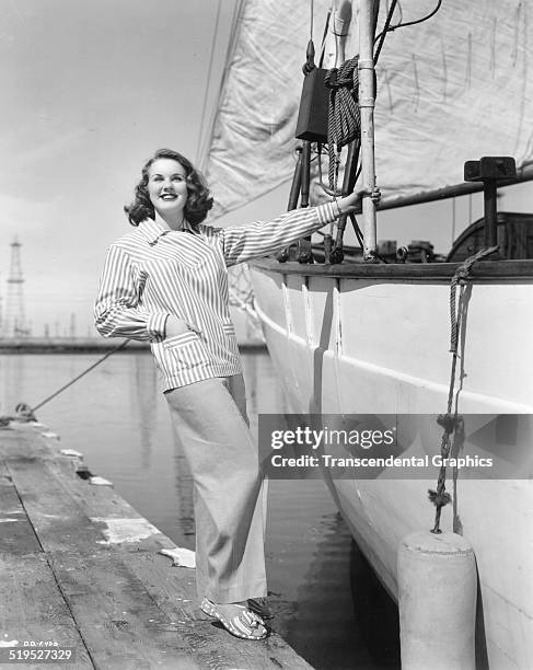 Portrait of Canadian-born American actress and model Deanna Durbin as he poses on a dock beside a sailboat, circa 1950.