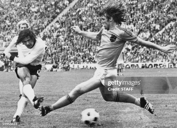 West German forward Gerd Muller scores the second goal for his team despite the being pressured by Dutch defender Rudi Krol, 07 July 1974 in Munich,...