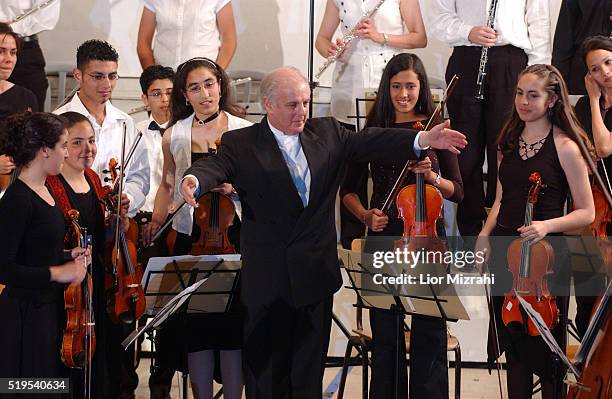 Israeli pianist and conductor Daniel Barenboim spreads his arms to congratulate the Palestinian Youth Orchestra who stand after finishing their...