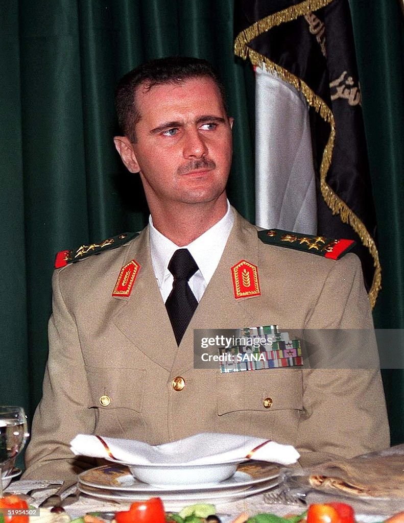 Syrian President Bashar al-Assad (R) attends a din