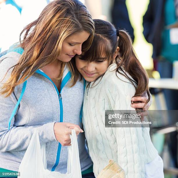 mother and daughter receive donations at charity event - homeless child stock pictures, royalty-free photos & images