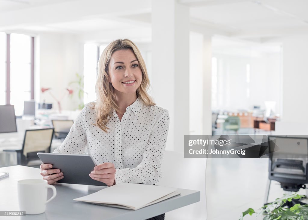 Mid adult businesswoman with tablet, looking away