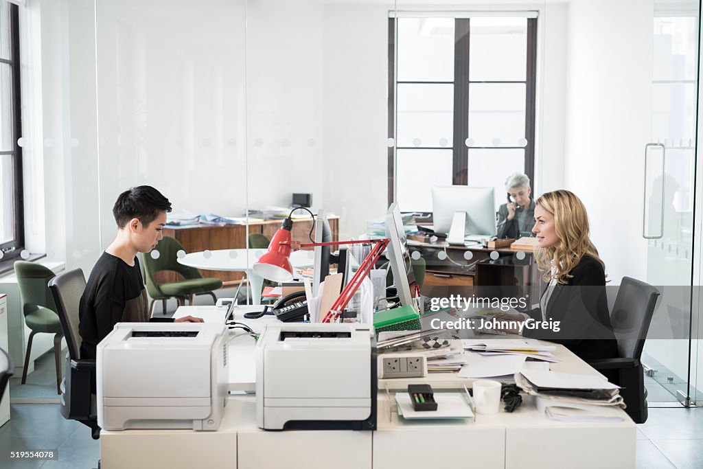 Businesswomen sitting at desk in modern office using computers