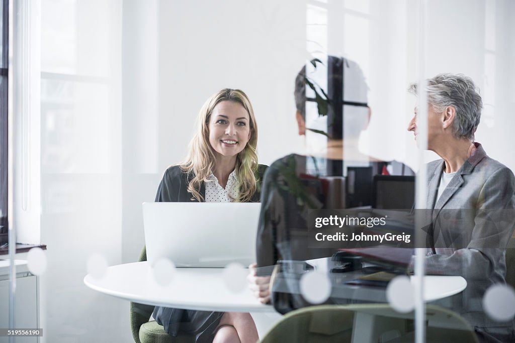 Female colleagues behind glass screen in meeting room