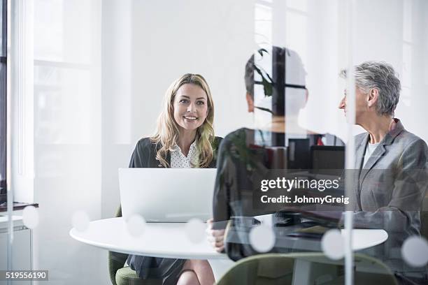 female colleagues behind glass screen in meeting room - business meeting three people stock pictures, royalty-free photos & images