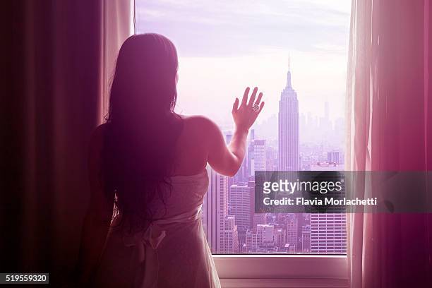 young woman with hand on window and new york skyline - grand plans for new home stock pictures, royalty-free photos & images