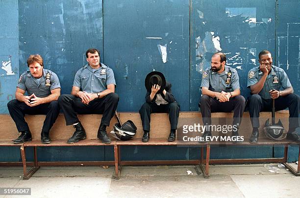 Young Hasidic child covers his face as he sits on a bench with New York City Police officers 24 August 1991 after more than 1,000 protesters walked...