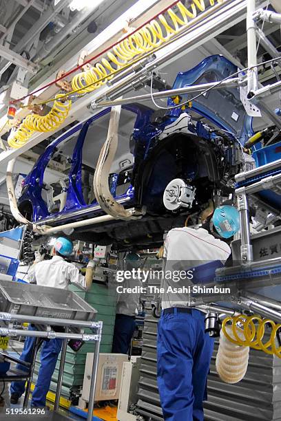 Workers assemble cars on a production lines of the Daihatsu Motor Co's Oita Daini Factory is seen during a media tour on April 6, 2016 in Nakatsu,...