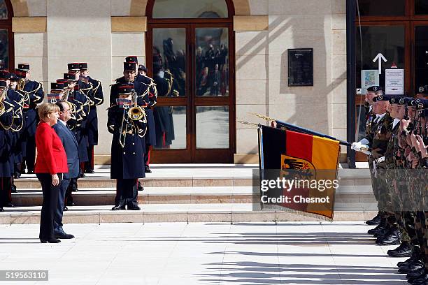 French President Francois Hollande and German Chancellor Angela Merkel walk past Republican Guards as they arrives to the 18th Franco-German cabinet...