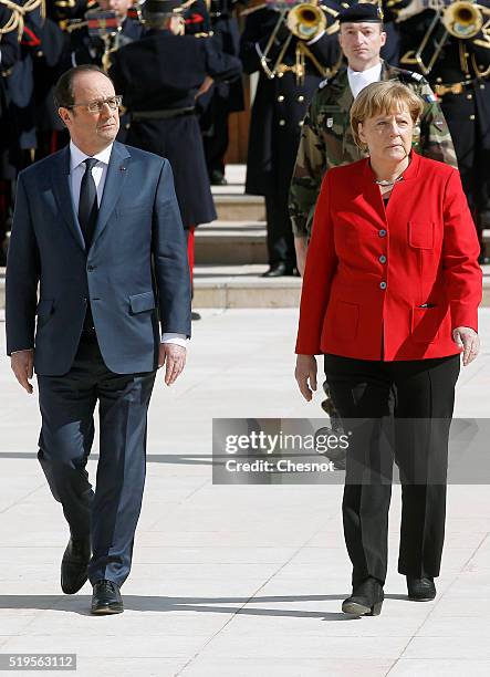 French President Francois Hollande and German Chancellor Angela Merkel walk past Republican Guards as they arrives to the 18th Franco-German cabinet...