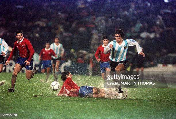 Gabriel Batistuta de Argentina se lleva la pelota superando al chileno Lizardo Garrido que cae en el agua durante el partido por la Copa America...
