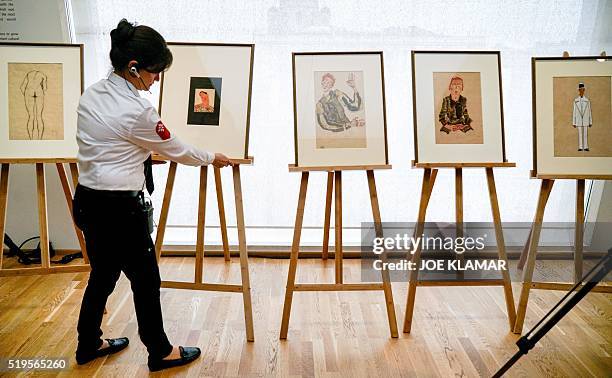 Security woman adjusts one of five drawings by Austrian painter Egon Schiele displayed during a press conference at Vienna's famous Leopold Museum in...