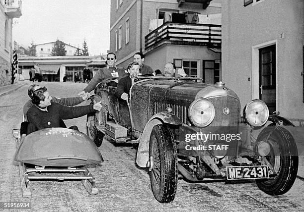 The two-man bobsleigh team from Great Britain greets passengers riding in a Bentley 25 February 1956 in the streets of Cortina d'Ampezzo, on the eve...