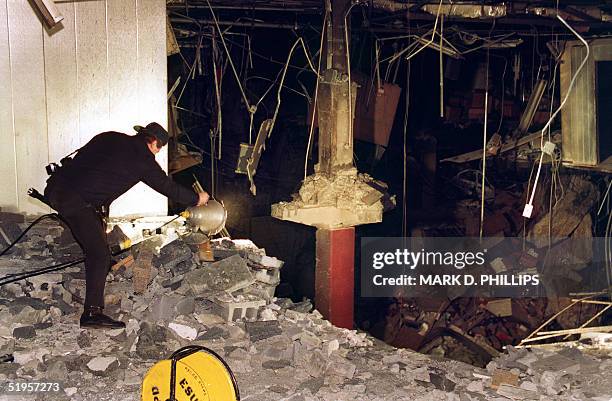 Police photographer adjusts a light at the edge of the crater in an underground parking garage at the World Trade Center 28 February 1993. The...