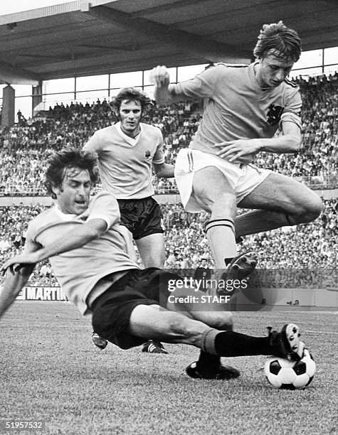 Dutch forward Johan Cruijff jumps to avoid the tackle of Uruguayan defender Ricardo Pavoni as defender Baudilio Jauregui looks on, 15 June 1974 in...