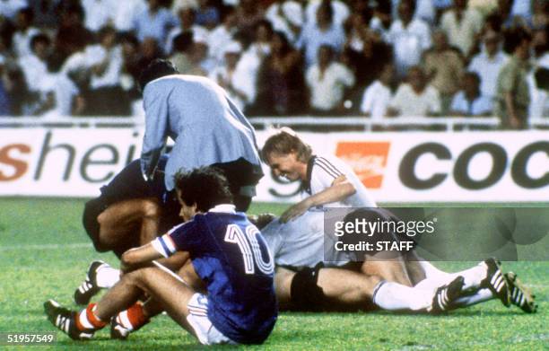 West German players celebrate after forward Horst Hrubesch scored the winning penalty kick in extra time as French midfielder Michel Platini sits on...