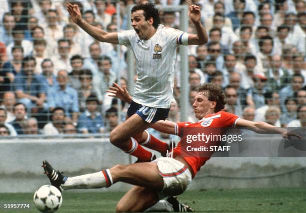 French midfiedler Michel Platini loses control of the ball as he is tackled by English defender Terry Butcher during the World Cup first round soccer...