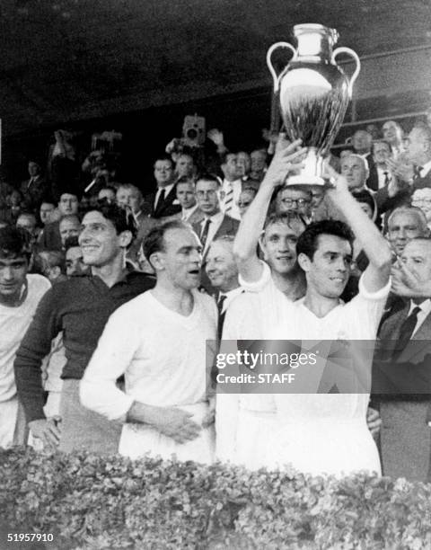 Real Madrid's captain Jose Santamaria, with teammates Rogelio Dominguez and Alfredo Di Stefano standing next to him, holds aloft the European...