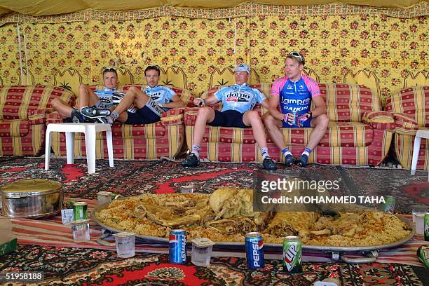 Unidentified cyclists rest in a tent in front of a large platter of traditional Qatari food before the start of the fourth stage of the Tour of Qatar...