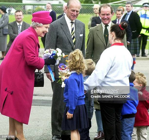 Britain's Queen Elizabeth II receives flowers from school children as the Duke of Edinburgh watches, during a tour of Portree on the Isle of Skye 27...