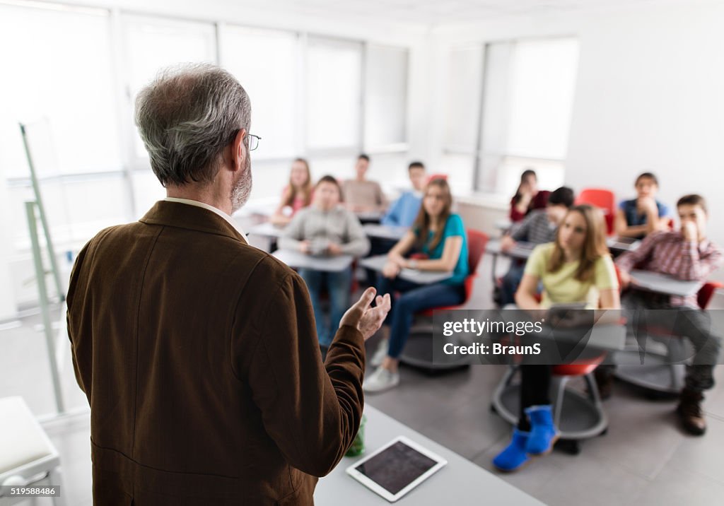Rear view of a male teacher giving a lecture.
