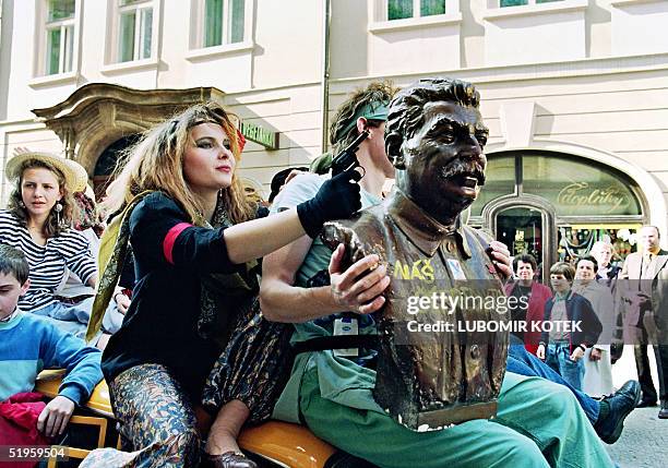 Prague' student aims 01 May 1990 in Prague a toy gun at the statue of Soviet dictator Stalin wearing a writing reading: "Our editor-in-chief" during...