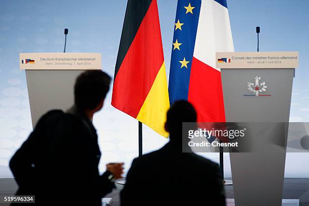 Journalists look at German, European and French flags prior to a press conference during the 18th Franco-German cabinet meeting on April 07, 2016 in...