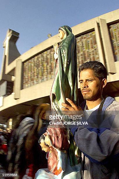 Man carries a statue of the Virgin Mary 12 December 1999 in Mexico City. Un joven carga una imagen de la Virgen en el atrio de la Basilica de...