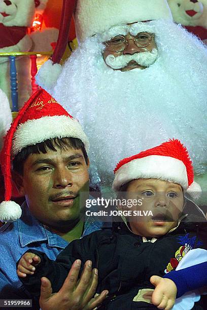 Mexican father and his son pose for a photograph with Santa Claus 23 December during Christmas celebrations in Mexico City. Una hombre con su hijo se...