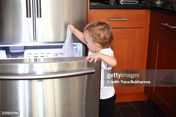 little boy opened the freezer door and taking things out - child proofing stock pictures, royalty-free photos & images