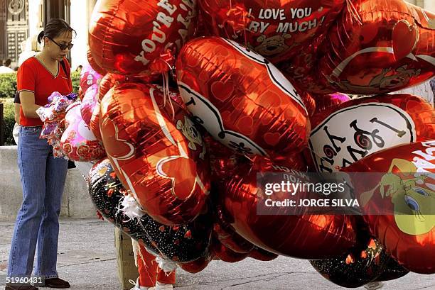 Young woman buys a heart-shaped balloon from an outdoor vendor on Valentine's Day, 14 February 2000, Mexico City, Mexico. Una joven compra un globo...