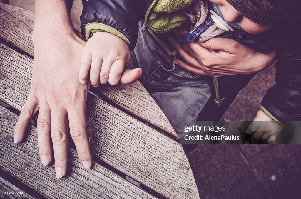 Mother and baby child holding hands on wooden table background