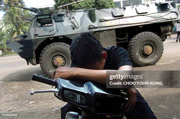 An Indonesian takes a break in front of Indonesian military armored car which guarding the city street in Banda Aceh 14 January 2005, three weeks...