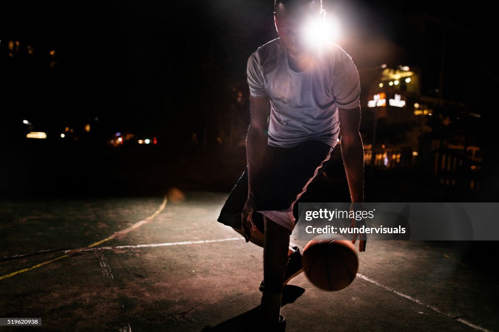 Hombre de jugador de baloncesto driblar Bola en Tribunal en la noche