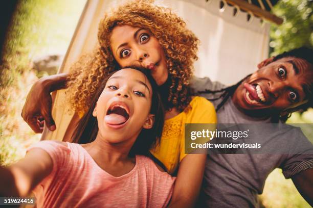 lovely african-american family making silly faces and posing - quirky family stockfoto's en -beelden